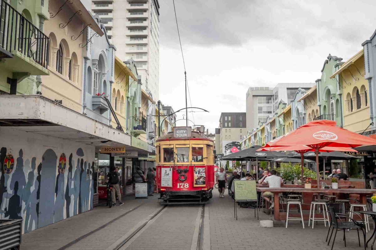 Red tram on a street with colorful buildings and outdoor cafes