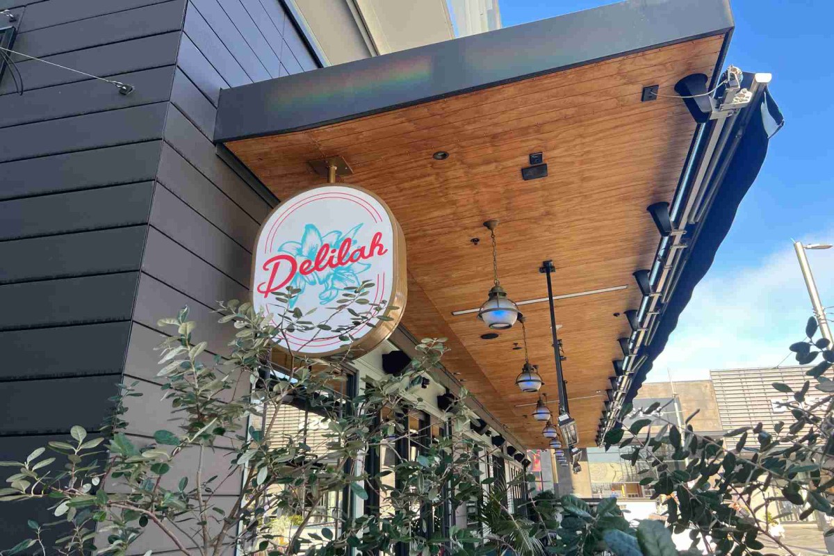 Restaurant exterior with a round hanging sign that says "Delilah."