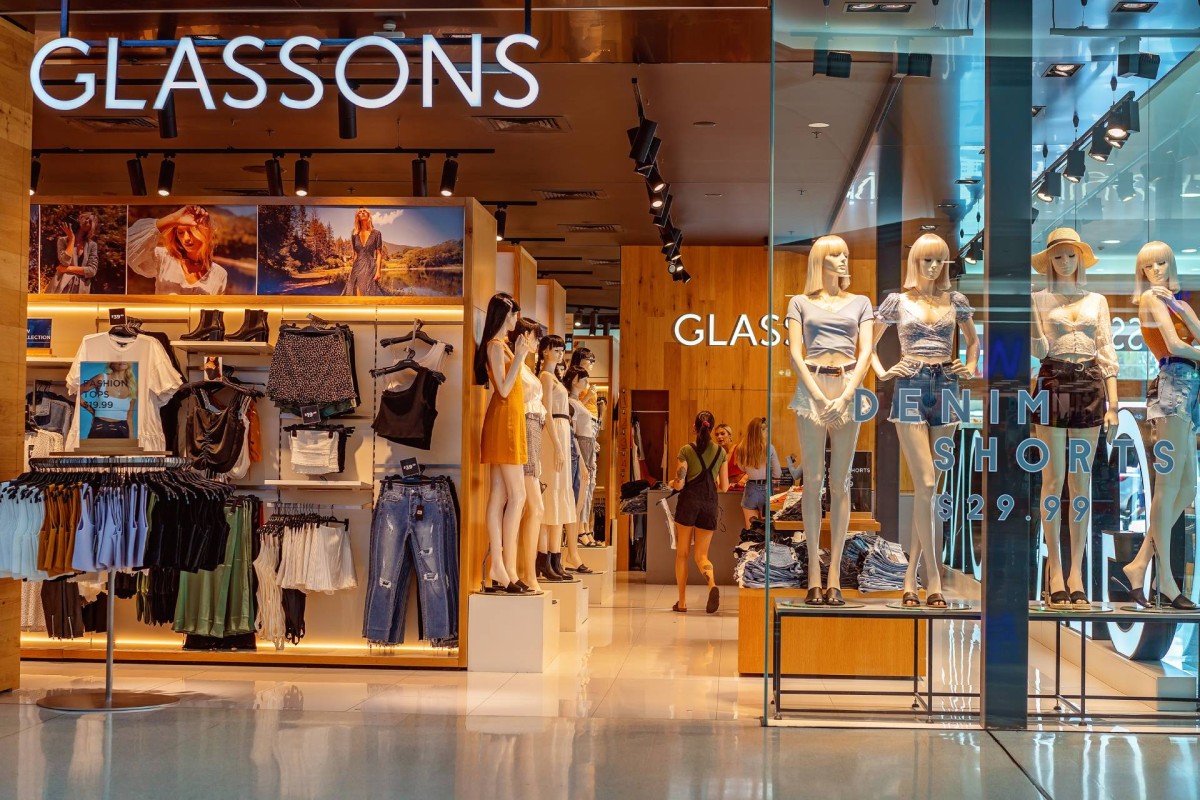 Clothing store display with mannequins, racks of clothes, and a large “Glassons” sign at the entrance