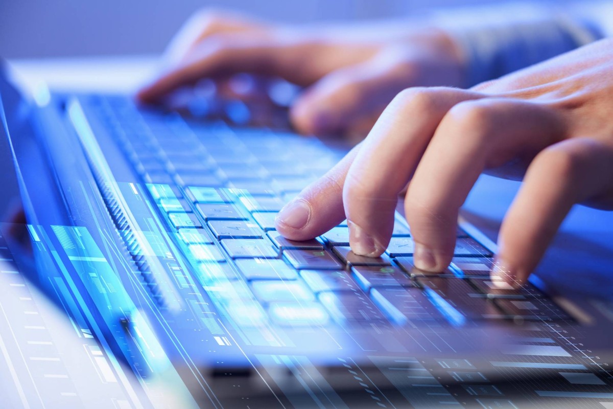 Hands typing on a laptop keyboard with a blue, futuristic digital overlay.