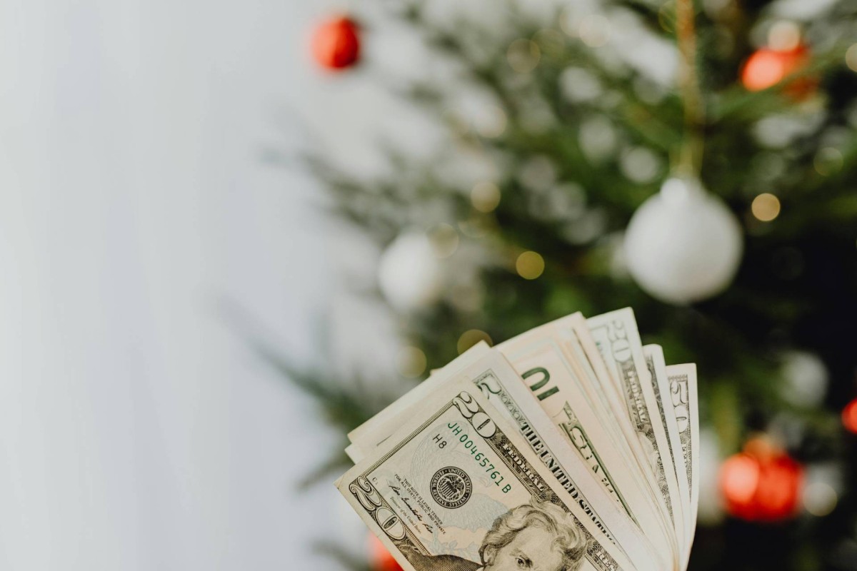 Cash held in front of a decorated Christmas tree