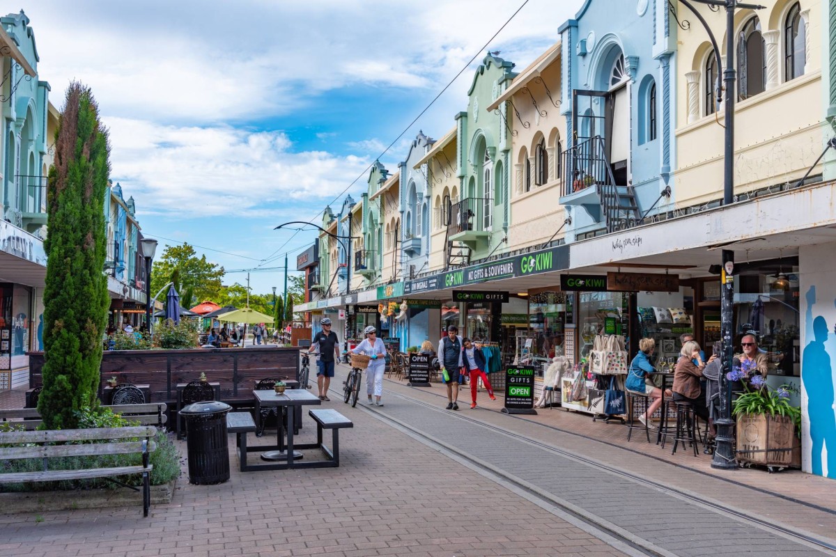 People walking and dining along a colourful shopping street with cafés and shops