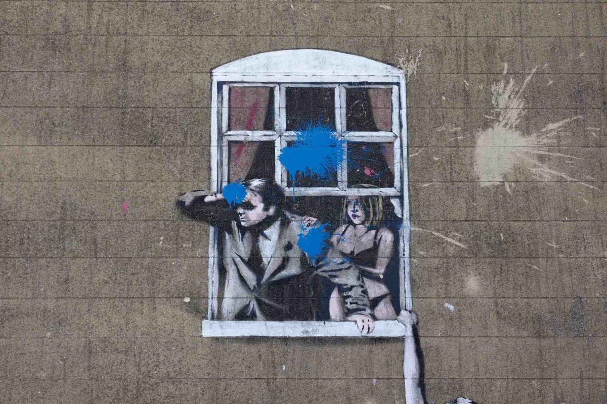 Couple looking out window in street art mural