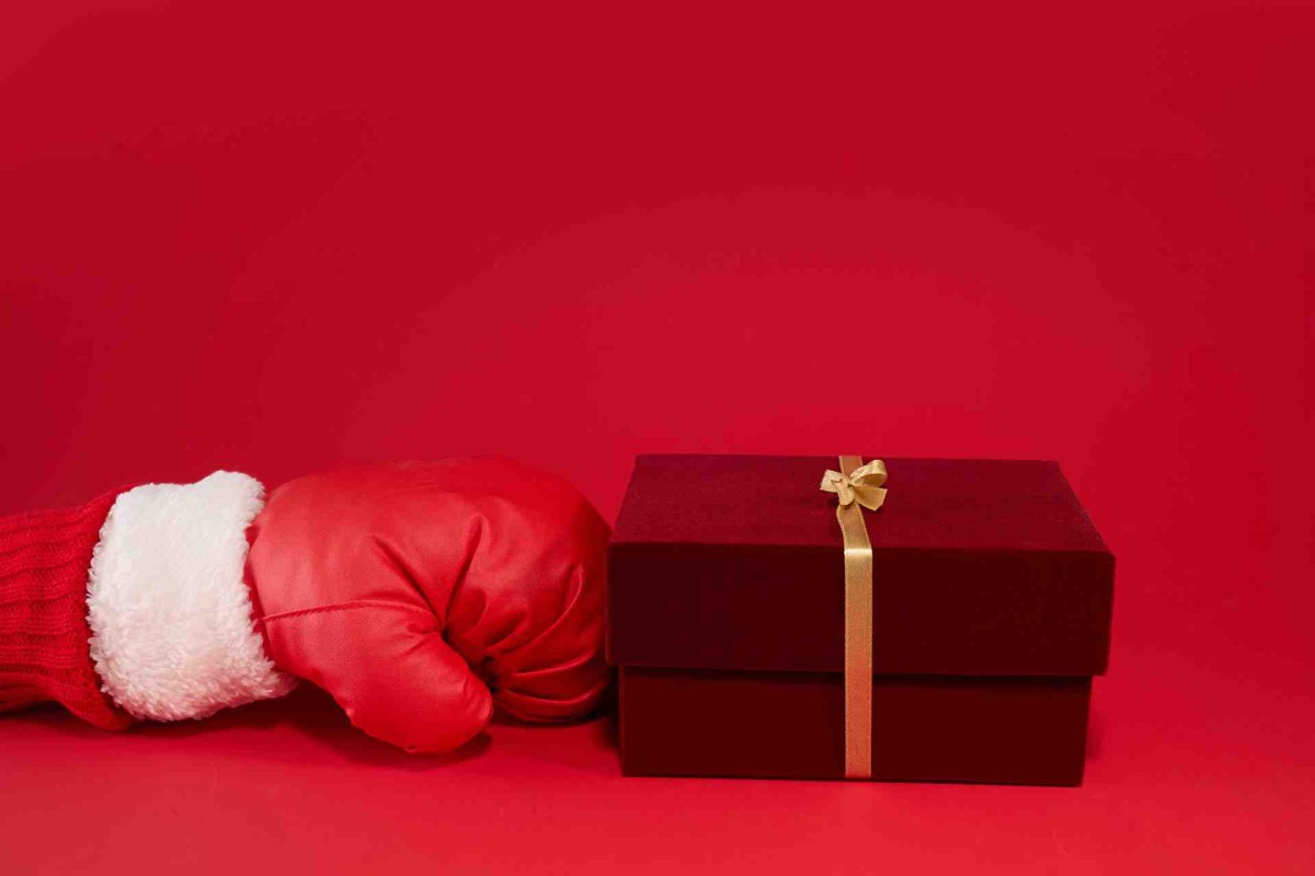 Boxing glove next to a wrapped gift box on a red background