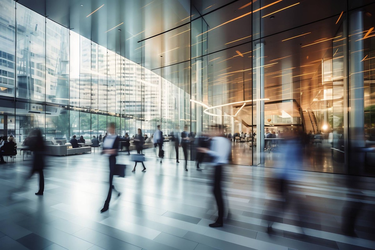 People walking through a modern office building lobby with glass walls