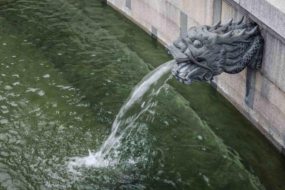 Dragon fountain pouring water into a green pond