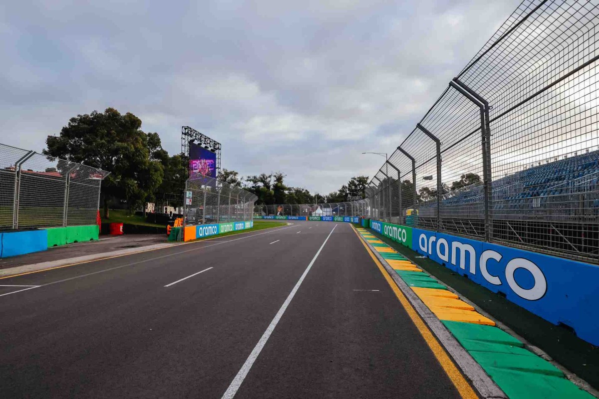 An empty Formula racing track lined with barriers and fencing under a cloudy sky