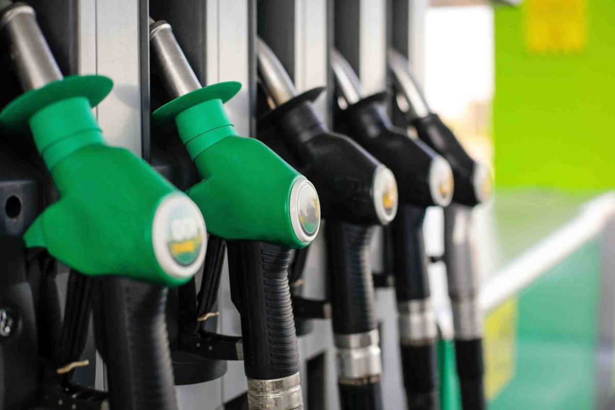 Close-up of green and black fuel pump nozzles lined up at a gas station