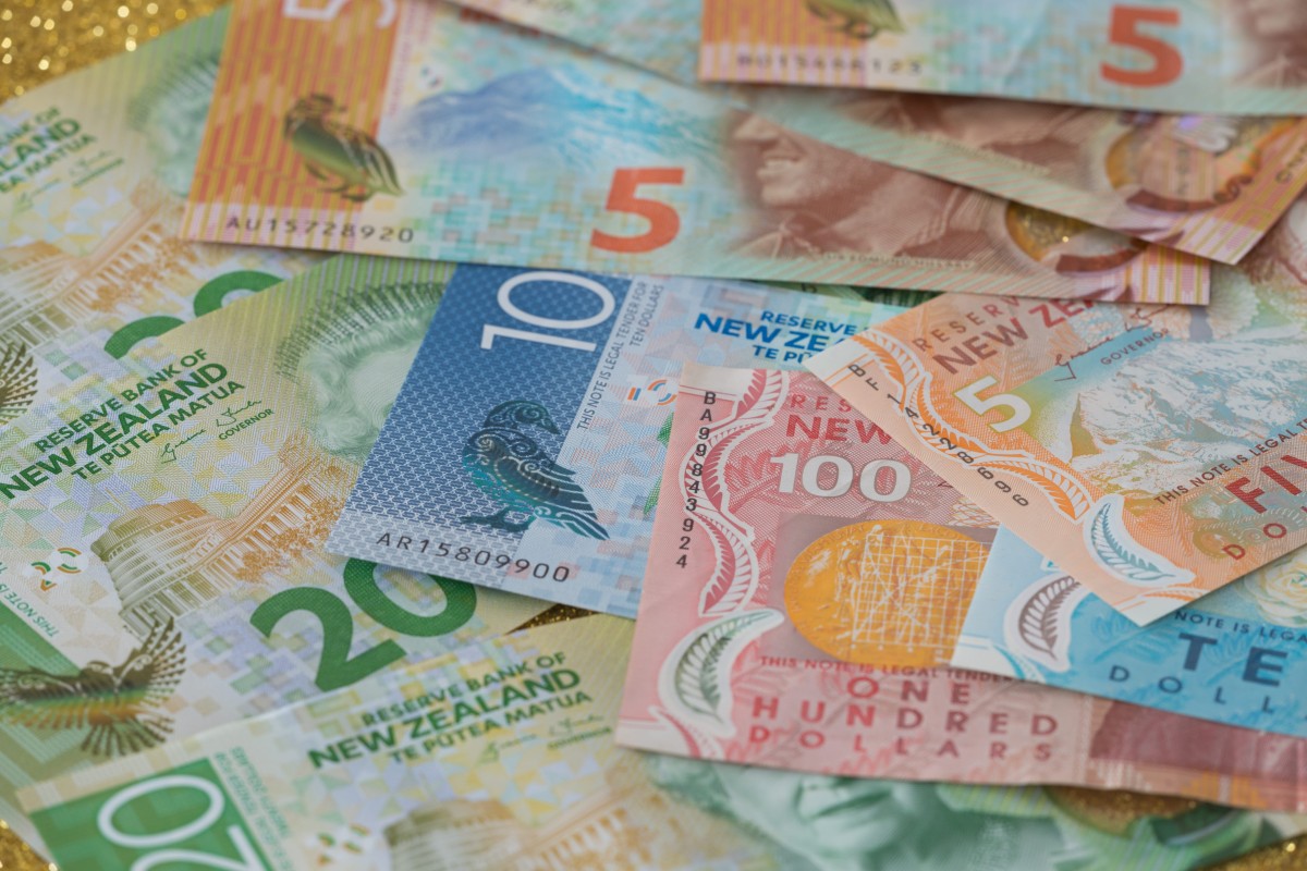 Colorful New Zealand banknotes of various denominations spread out, including $5, $10, $20, and $100 bills