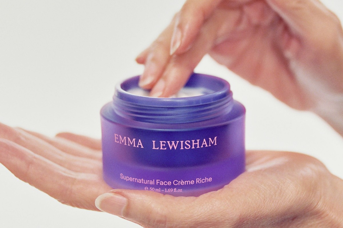 Hands holding a purple jar of face cream.