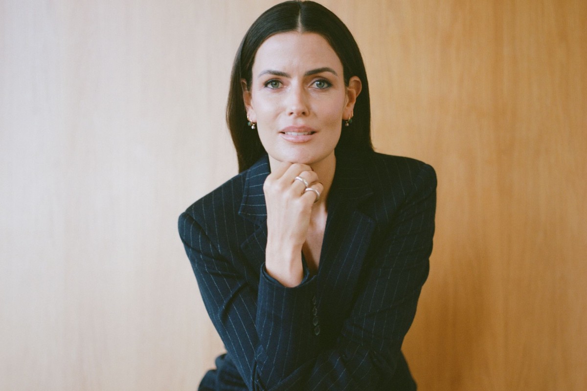 Woman in pinstripe blazer resting chin on hand.