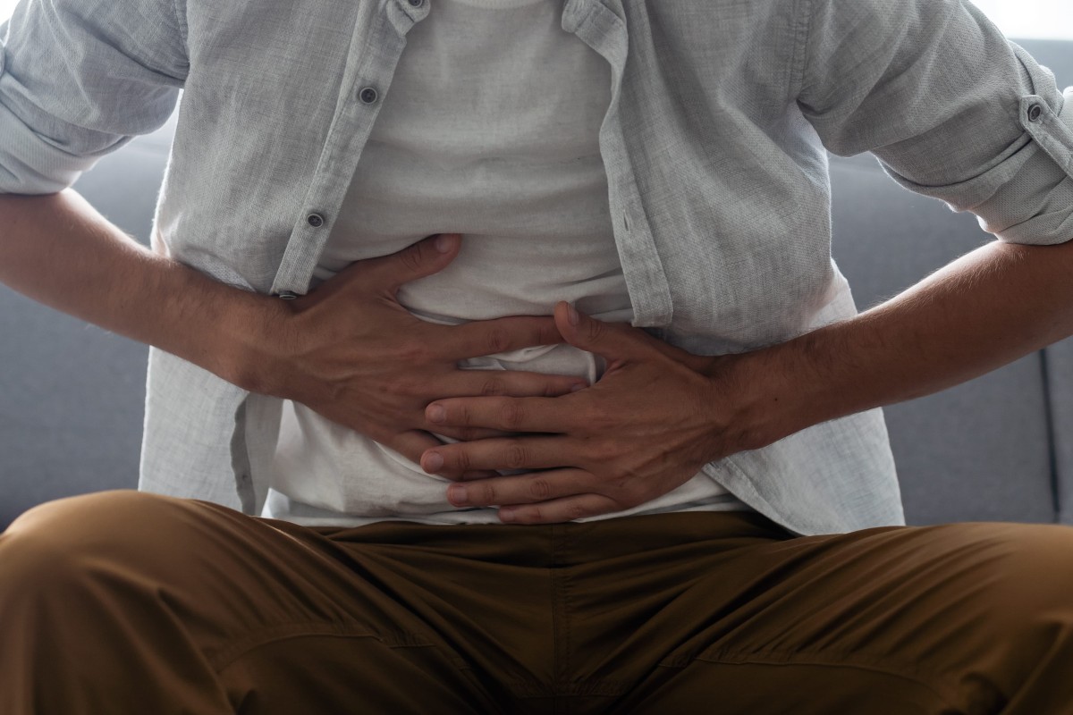 Person sitting and holding their stomach due to abdominal pain