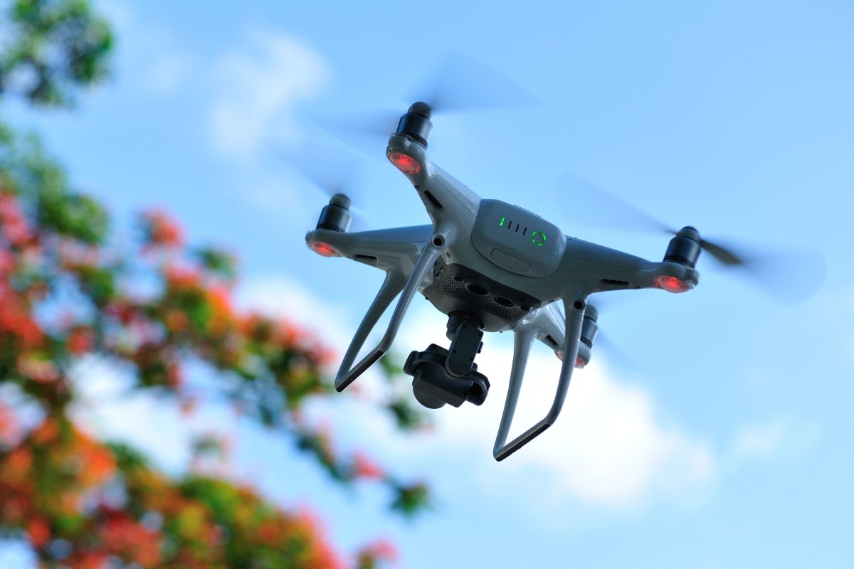 Drone flying against a clear blue sky above a residential neighbourhood
