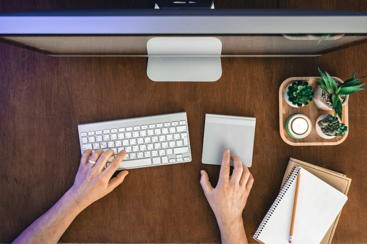 Person using a computer keyboard and trackpad at a tidy office desk