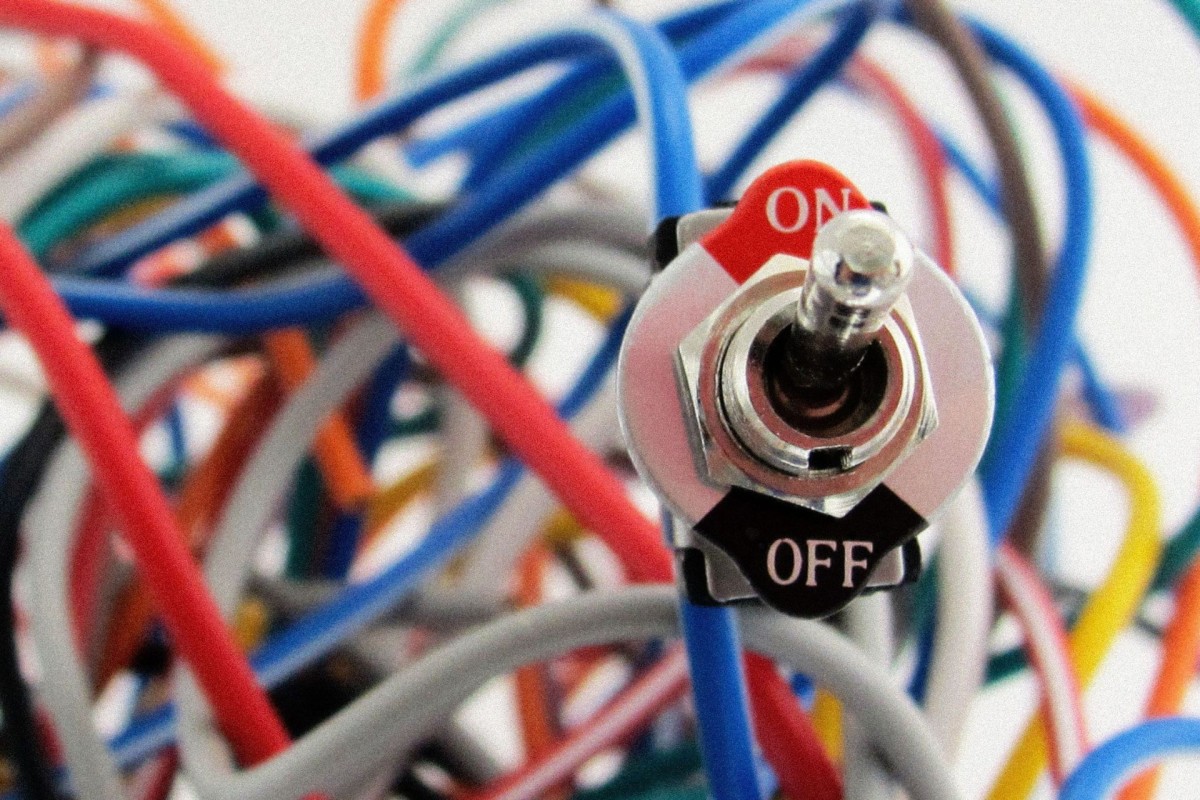 Close-up of an electrical switch marked “ON” and “OFF” surrounded by colourful electrical wires.