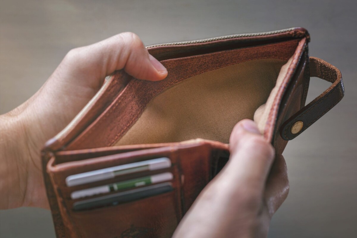 Person holding an empty wallet, illustrating financial hardship and the decision to wind up a struggling business.